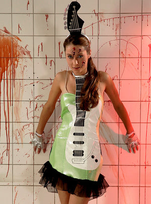 Eine Frau steht vor einer blutbespritzten Fliesenwand und trägt das „Disco 2. Wahl Gitarrenkostüm“ – ein glänzendes Kleid und einen Kopfschmuck mit Gitarrenmotiv –, dazu Halloween-Make-up und Handschuhe mit Skelettmuster.