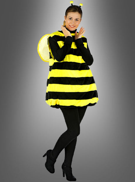 Eine Person steht lächelnd auf einem Bein und trägt ein Plüsch-Bienenkostüm für Erwachsene mit schwarzen Leggings, schwarzen Schuhen und einem Stirnband mit gelben Fühlern – perfekt als lustiges Karnevals- oder Faschingskostüm.