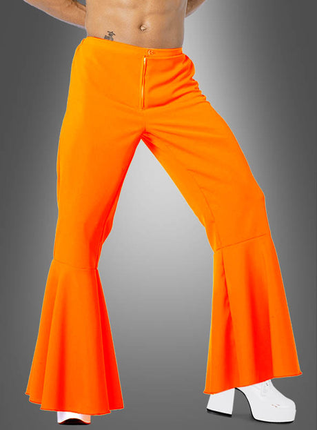 Eine Person in einer leuchtend orangefarbenen Neon-Schlaghose für Herren und weißen Plateauschuhen, die vor einem grauen Hintergrund mit Farbverlauf steht – das perfekte 70er-Jahre-Outfit.