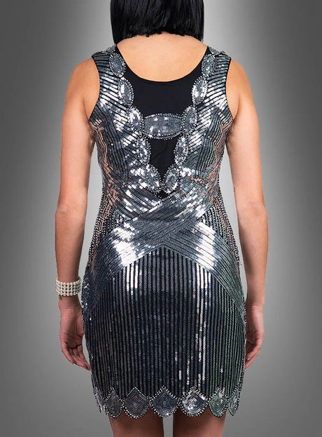 Eine Person, die das „Premium Paillettenkleider Ruby“ trägt – ein ärmelloses, silber-schwarzes Paillettenkleid und ein exquisites Beispiel für ein Kleid im Stil der 20er Jahre –, ist von hinten vor einem grauen Hintergrund mit Farbverlauf zu sehen.