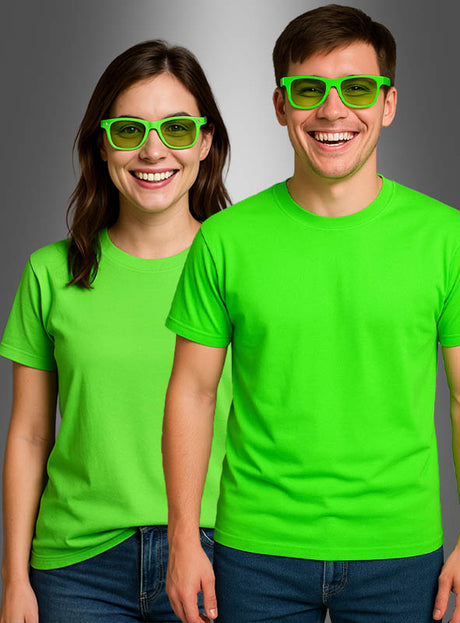 Zwei Personen stehen nebeneinander vor einem neutralen grauen Hintergrund; beide tragen das Neon-T-Shirt „Damen und Herren“ in leuchtendem Grün sowie dazu passende grüne Brillen und versprühen damit eine ausgelassene 80er-Jahre-Atmosphäre.