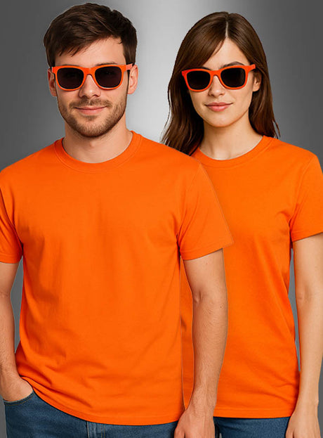 Zwei Personen, die identische Neon-T-Shirts für Damen und Herren – leuchtend orangefarbene T-Shirts – sowie knallorangefarbene Sonnenbrillen tragen, stehen Seite an Seite vor einem grauen Hintergrund und verkörpern den ikonischen Stil der 80er Jahre.