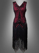 Ärmelloses, burgunderrotes Luxus-Flapperkleid „Iris“ mit doppelter Knopfleiste, schwarzen Paillettenakzenten und langen Fransen am Saum, präsentiert vor einem schlichten grauen Hintergrund mit Farbverlauf – ideal, um den Glamour eines Paillettenkleids im Stil der 20er Jahre einzufangen.