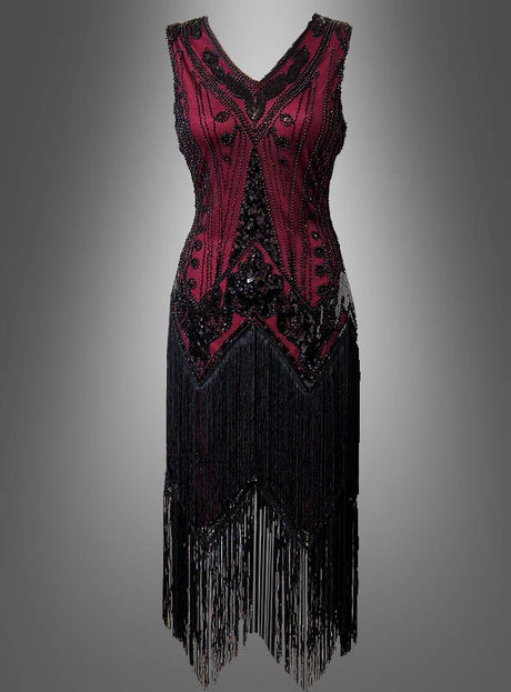 Ärmelloses, burgunderrotes Luxus-Flapperkleid „Iris“ mit doppelter Knopfleiste, schwarzen Paillettenakzenten und langen Fransen am Saum, präsentiert vor einem schlichten grauen Hintergrund mit Farbverlauf – ideal, um den Glamour eines Paillettenkleids im Stil der 20er Jahre einzufangen.