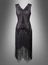 Das Luxus-Flapperkleid „Doppelreiher Iris“ ist ein ärmelloses schwarzes Kleid mit aufwendigen Perlenverzierungen und langen Fransen am Saum, das den Charme eines klassischen Kleides aus den 20er Jahren einfängt und vor einem grau verlaufenden Hintergrund präsentiert wird.