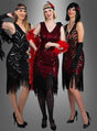 Drei Frauen in Flapper-Kleidern mit Fransen im Stil der 1920er Jahre – eine strahlt im „Exklusives 20er Flapper Kleid Vivian“, eine andere funkelt in einem Paillettenkleid – tragen Stirnbänder, Federboas und hohe Absätze, während sie gemeinsam vor einem grauen Hintergrund posieren.