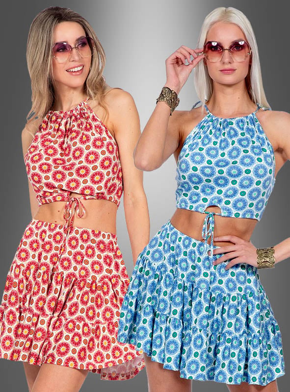 Zwei Frauen, die passende Sommer-Outfits aus Rock und Oberteil im Boho-Stil tragen – die eine in Rot und Gelb, die andere in Blau und Grün –, posieren vor einem grauen Hintergrund mit Farbverlauf. Ihr aufeinander abgestimmter Look besticht durch kokette Miniröcke und einen verspielten Boho-Stil, wodurch sich diese Outfits perfekt für lebhafte Sommertage eignen.