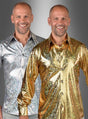 Zwei lächelnde Männer stehen nebeneinander, der eine trägt ein glänzendes silbernes „Deluxe 70er Disco Hemd Hologramm“, der andere eine schillernde goldene Version desselben Hemdes, vor einem grau verlaufenden Hintergrund – sie verkörpern den pulsierenden Geist einer 70er-Jahre-Disco-Party.
