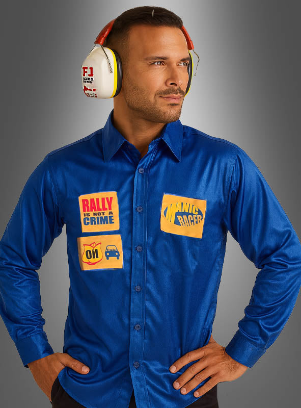 Ein Mann, der das „Formel-1-Rennfahrer“-Shirt zum Sonderpreis trägt – ein blaues Satinhemd mit Rennsport-Aufnähern –, kombiniert mit weißen F1-Kopfhörern mit Geräuschunterdrückung, steht vor einem grauen Hintergrund.