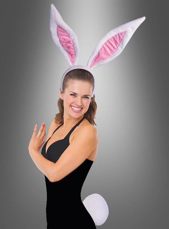 Eine Frau trägt den Catsuit Overall in Schwarz, dazu große rosa-weiße Hasenohren und einen weißen, flauschigen Schwanz, und steht vor einem grauen Hintergrund mit Farbverlauf.
