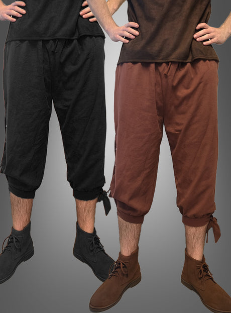 Zwei Personen tragen die „Mittelalter Hose Herren“ – kurze Hosen mit Kordelzug in Schwarz und Braun –, die sich perfekt für LARP oder als Teil eines Wikinger-Kostüms eignen. Beide haben die Hände in die Hüften gestemmt und tragen braune Stiefeletten. Die Hosen sind an den Waden zusammengebunden, um einen authentischen mittelalterlichen Look zu erzielen.