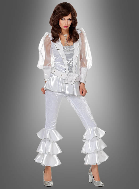 Eine Frau präsentiert den „70er-Jahre-Disco-Anzug für Damen“ – ein glänzendes, silbernes Outfit im Stil der 1970er Jahre mit Schlaghose, Rüschenärmeln und hochhackigen Schuhen –, das sich perfekt als Disco-Kostüm für Damen oder ABBA-Kostüm eignet, während sie vor einem grauen Hintergrund mit Farbverlauf posiert.