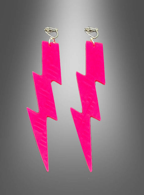 Ein Paar Ohrringe im Stil der 80er Jahre – „Neon Blitz“-Ohrringe in leuchtendem Pink in Form von Blitzen mit Metallhaken, vor einem grauen Hintergrund mit Farbverlauf.