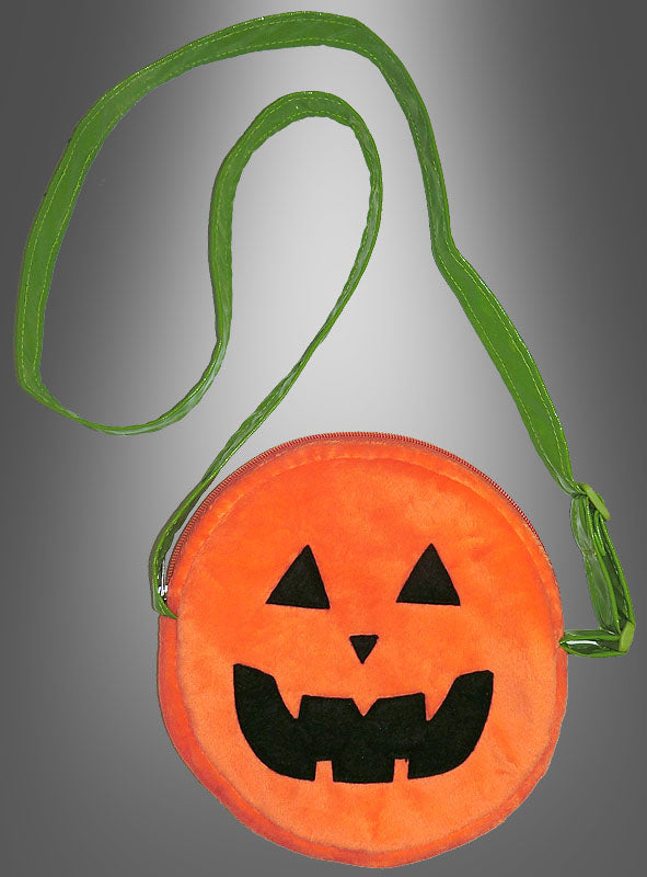 Eine runde orangefarbene Tasche mit einem schwarzen Kürbiskopf und einem langen grünen Riemen vor einem grauen Hintergrund mit Farbverlauf – diese verspielte „Kürbis-Umhängetasche zum Kostüm“ ist das perfekte Halloween-Accessoire für festliches Flair.