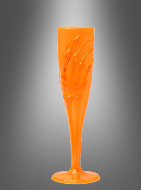 Das „Skeletthand Sektglas 20 cm“, ein orangefarbenes Sektglas aus Kunststoff mit einem Skeletthand-Motiv, wird vor einem schattierten grauen Hintergrund präsentiert – perfekt als Halloween-Tischdeko für Ihre nächste Gothic-Party oder gruselige Feier.
