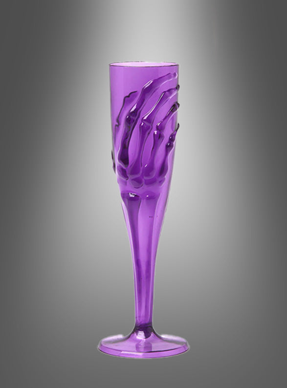 Ein lilafarbenes „Skeletthand“-Sektglas (20 cm) mit einer reliefartig gestalteten Skeletthand, die sich um den Kelch schmiegt und vor einem grau abgestuften Hintergrund hervorsticht – ideal für Ihre Halloween-Tischdekoration oder um jeder Gothic-Party eine unheimliche Eleganz zu verleihen.