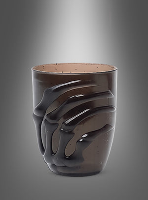 Vor einem sanft beleuchteten, grau abgestuften Hintergrund präsentiert sich das „Halloween Glas 10 cm mit Skelett-Hand“ mit einer glänzend schwarzen, plastisch geformten Skelett-Hand, die sich an seiner dunklen Keramikoberfläche festhält – ein Blickfang, der sich perfekt als auffällige Tischdekoration eignet oder zum Servieren Ihres Lieblings-Halloween-Getränks.
