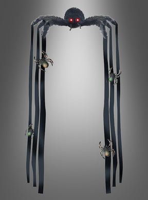 Eine riesige Deko-Spinne (90 cm), mit roten Augen und langen, bandartigen Beinen, verziert mit kleineren Spinnen, hängt vor einem schlichten grauen Hintergrund – perfekt, um Ihrer Halloween-Dekoration einen gruseligen Touch zu verleihen.