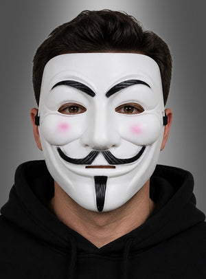 Eine Person, die die „Weiße Maske mit Bart“ trägt – mit schwarzen Details und rosa Wangen im Stil einer Guy-Fawkes-Maske – und einen schwarzen Kapuzenpulli anhat, posiert vor einem grauen Hintergrund mit Farbverlauf.