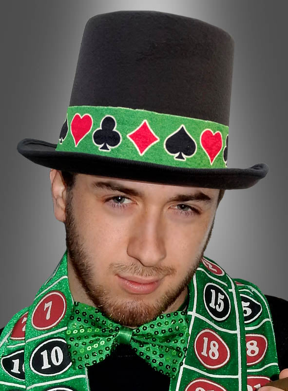 Ein Mann, der einen schwarzen Zylinderhut mit Kartensymbolen, eine grüne Fliege und ein Hutband für Casino-Kostüme trägt und vor einem grauen Hintergrund posiert – als Teil seiner Casino-Kostümaccessoires.