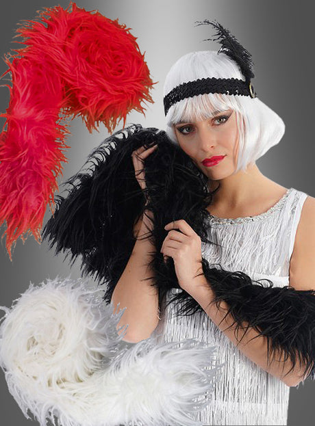 Eine Frau in einem weißen Flapper-Kleid und einer Perücke hält eine schwarze Kunstfell-Federboa im Stil der 20er Jahre (210 cm) in der Hand, während neben ihr auf einem Hintergrund mit Farbverlauf rote und weiße Kunstfell-Federboas im Stil der 20er Jahre (210 cm) zu sehen sind.