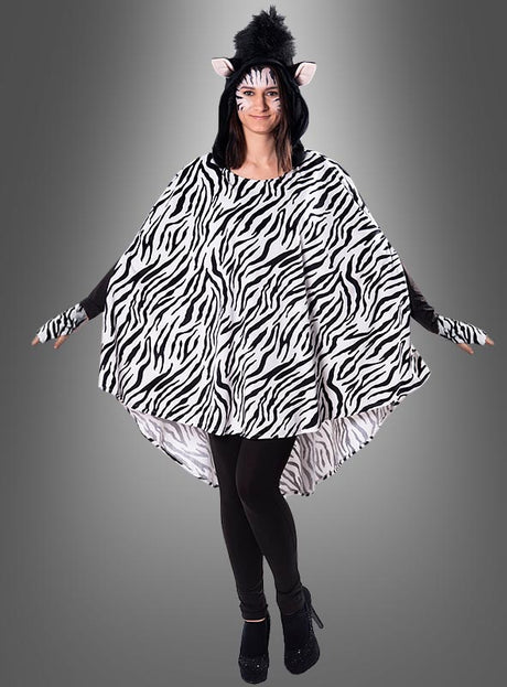 Ein Model trägt den Plüsch-Zebra-Poncho in den Größen XS–XXXL mit auffälligen schwarz-weißen Streifen, dazu einen Kopfschmuck mit Zebra-Ohren, Gesichtsbemalung und schwarze Leggings; es steht mit leicht ausgestreckten Armen vor einem grauen Hintergrund.