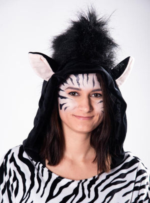 Eine Frau, die den Plüsch-Zebra-Poncho in den Größen XS bis XXXL trägt – mit einer Kapuze mit Ohren und einer detailreichen Gesichtsbemalung im Zebrastreifen-Look –, steht vor einem einfarbigen Hintergrund.