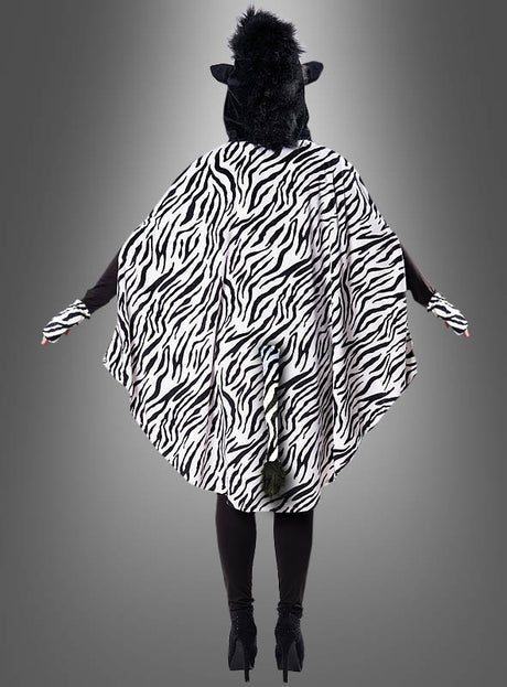Eine Person, die den Plüsch-Zebra-Poncho in den Größen XS bis XXXL trägt – komplett mit Kapuze, Handschuhen und Umhang –, steht vor einem grauen Hintergrund und wird von hinten gezeigt.