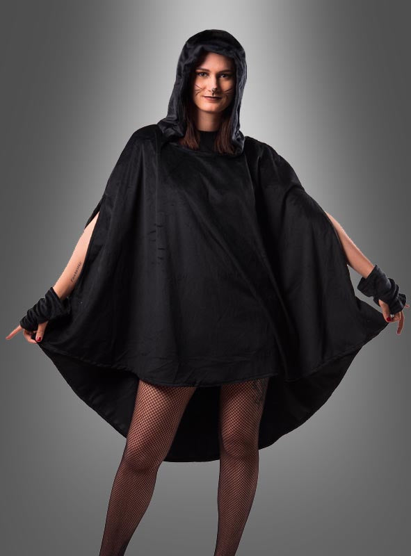 Eine Person, die einen schwarzen Kapuzenmantel und fingerlose Handschuhe trägt, dazu Netzstrümpfe und den wandelbaren schwarzen Poncho aus Plüsch (XS–XXXL), vor einem grauen Hintergrund mit Farbverlauf – perfekt, um einen auffälligen Karnevalslook zu kreieren.