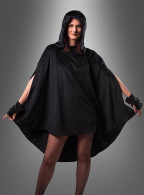 Eine Person, die einen schwarzen Kapuzenmantel und fingerlose Handschuhe trägt, dazu Netzstrümpfe und den wandelbaren schwarzen Poncho aus Plüsch (XS–XXXL), vor einem grauen Hintergrund mit Farbverlauf – perfekt, um einen auffälligen Karnevalslook zu kreieren.