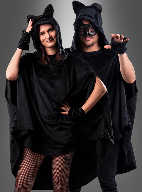 Zwei Personen in schwarzen Katzenkostümen – mit Kapuzen mit Ohren, Katzen-Make-up und schwarzen Handschuhen – posieren vor einem neutralen Hintergrund. Abgerundet wird ihr Outfit durch den „Wandelbaren schwarzen Poncho aus Plüsch XS-XXXL“, der eine gemütliche und verspielte Note verleiht, die perfekt für Karnevalsfeiern ist.