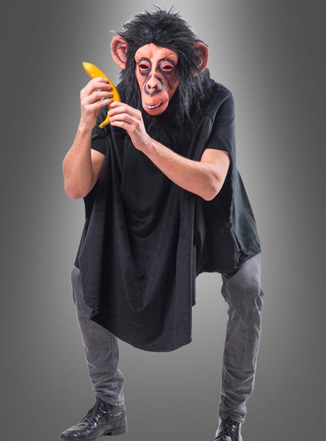 Eine Person, die eine Schimpansenmaske und einen schwarzen Umhang trägt, hockt vor einem grauen Hintergrund, hält eine gelbe Banane in der Hand und bewundert sie. Sie trägt den „Wandelbaren schwarzen Poncho aus Plüsch XS-XXXL“, der die verspielte Karnevalsatmosphäre der Szene unterstreicht.