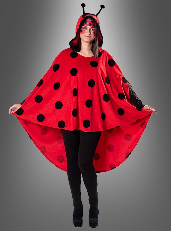 Eine Person, die einen „Marienkäfer“-Poncho aus Plüsch in den Größen XS–XXXL mit roten und schwarzen Punkten als bezauberndes Karnevalskostüm trägt, komplett mit Antennen-Stirnband und Gesichtsbemalung, steht mit ausgestreckten Armen da.