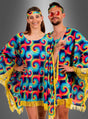 Zwei Personen posieren in aufeinander abgestimmten, farbenfrohen Tie-Dye-Outfits, die den Geist eines echten 70er-Jahre-Kostüms perfekt einfangen. Eine Person trägt einen „Hippie-Poncho für Damen mit Batikmuster“, der mit verspielten gelben Fransen verziert ist, während ihre Begleiterin den lebhaften Batik-Look mit einer Sonnenbrille und einem Stirnband abrundet. Die Szene spielt sich vor einem schlichten grauen Hintergrund mit Farbverlauf ab.