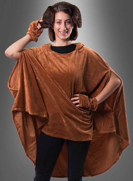Ein Model präsentiert den „Wandelbaren braunen Poncho aus Plüsch XS–XXXL“ mit passenden Armbändern und schlaffen Hundeohren und posiert dabei mit einer Hand in der Hüfte, während sie mit der anderen ein Ohr vor einem grauen Hintergrund hält – eine bezaubernde Präsentation dieses vielseitigen Tierponchos für Erwachsene.