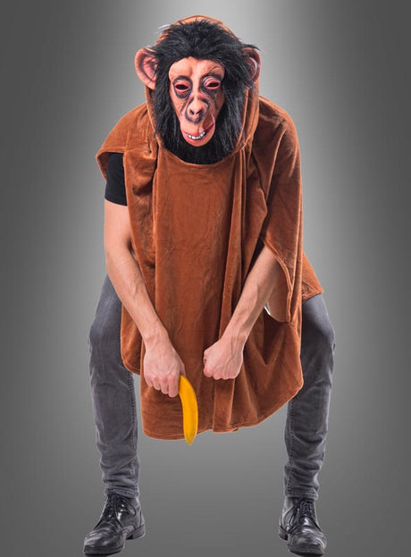 Eine Person, die eine Schimpansenmaske und den „Wandelbaren braunen Poncho aus Plüsch XS-XXXL“ trägt und eine gelbe Banane in der Hand hält, während sie vor einem grauen Hintergrund steht.
