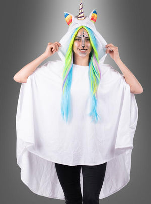 Vor einem grauen Hintergrund steht eine Person, die einen Einhorn-Poncho mit Kapuze, Regenbogenhorn, bunter Mähne und Gesichtsbemalung trägt. Dieser verspielte Look entsteht durch den „Wandelbaren weißen Poncho aus Plüsch S-XXXL“ – einen kuscheligen Plüschponcho, der sich perfekt für festliche Anlässe und Karnevalskostüme eignet.