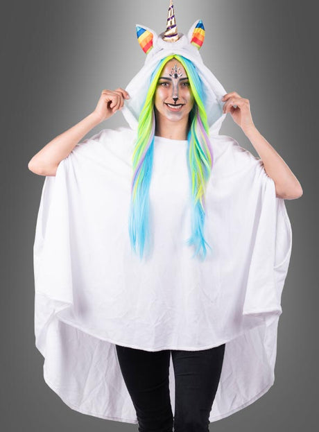 Vor einem grauen Hintergrund steht eine Person, die einen Einhorn-Poncho mit Kapuze, Regenbogenhorn, bunter Mähne und Gesichtsbemalung trägt. Dieser verspielte Look entsteht durch den „Wandelbaren weißen Poncho aus Plüsch S-XXXL“ – einen kuscheligen Plüschponcho, der sich perfekt für festliche Anlässe und Karnevalskostüme eignet.