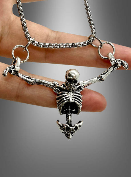 Eine Hand hält die „Silberne Skelett-Kette“ – ein Halloween-Schmuckstück, bestehend aus einer silbernen Kette mit einem Anhänger in Form eines ausgestreckten Skeletts –, vor einem grauen Hintergrund mit Farbverlauf.