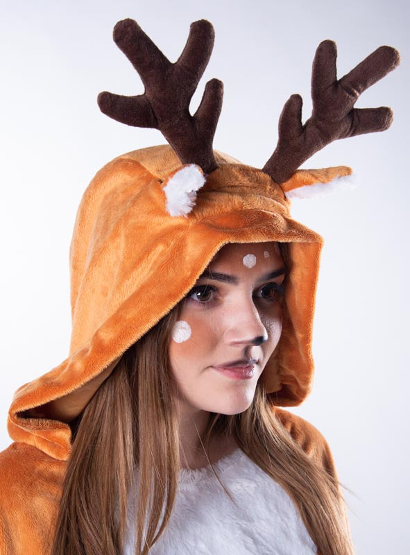 Vor einem einfarbigen Hintergrund ist eine Person zu sehen, die den „Kuschelweichen Reh-Poncho“ (S–XXXL) trägt, der eine braune Kapuze mit Geweih und weiße Punkte im Gesicht aufweist, um einem Rentier zu ähneln.
