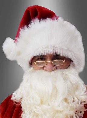 Eine Person, die eine „Nikolaus-Mütze Weihnachtsmann Deluxe“, eine Brille und einen weißen Bart trägt, blickt vor einem grauen Hintergrund mit Farbverlauf nach vorne.