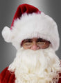 Eine Person, die eine „Nikolaus-Mütze Weihnachtsmann Deluxe“, eine Brille und einen weißen Bart trägt, blickt vor einem grauen Hintergrund mit Farbverlauf nach vorne.