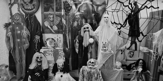 Ein Raum, der mit verschiedenen gruseligen Halloween-Requisiten dekoriert ist, darunter Geister, Skelette, Spinnweben, Kürbisse und schaurige Figuren, die zu einer gespenstischen Kulisse angeordnet sind.