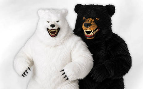 Zwei Personen in realistischen Kostümen als Eisbär und Schwarzbär stehen Seite an Seite vor einem schlichten weißen Hintergrund, beide mit offenem Maul, das ihre Zähne zeigt.