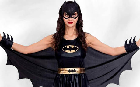 Eine Person in einem Batgirl-Kostüm mit schwarzer Maske, Fledermaus-Symbol auf der Brust, goldenem Gürtel und weit ausgebreitetem, geflügeltem Umhang.