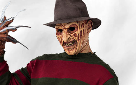 Eine Person mit einem braunen Fedora, einem grün-rot gestreiften Pullover, einer Maske mit vernarbten Gesichtszügen und einem Handschuh mit langen Metallklingen in der Hand.