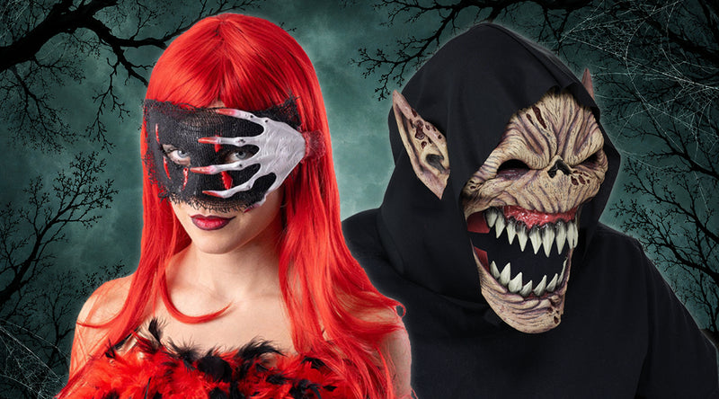 Zwei kostümierte Personen: eine mit langen roten Haaren, einer schwarz-weißen Maske und roten Federn; die andere mit einer Kapuze und einer Monstermaske mit scharfen Zähnen und spitzen Ohren. Im Hintergrund stehen blattlose Bäume.