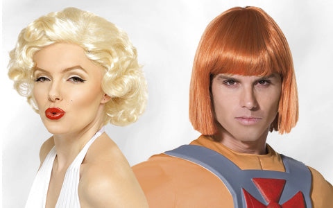 Eine Frau mit kurzen blonden Haaren und rotem Lippenstift posiert neben einem Mann mit glatten orangefarbenen Haaren, der ein Kostüm im Cartoon-Stil mit einem grauen Gurtzeug und einer orangefarbenen Rüstung trägt.