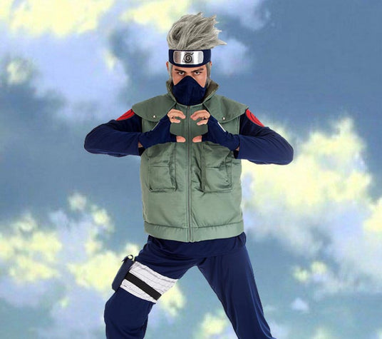 Eine Person in einer grünen Weste, einem blauen Outfit und einem Stirnband posiert vor einem Himmelhintergrund und formt mit beiden Händen vor der Brust ein Handzeichen.