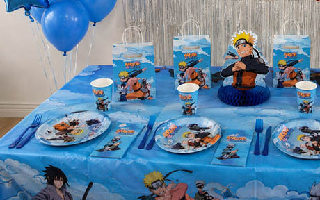 Ein Tisch ist für eine Party gedeckt, mit Tellern, Bechern, Servietten, Geschenktüten und Dekorationen zum Thema Naruto. Im Hintergrund sind blaue Luftballons und silberne Luftschlangen zu sehen.